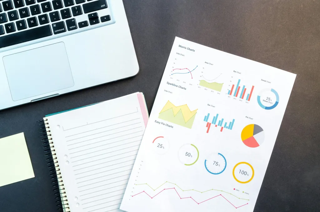 A workspace featuring a notebook, laptop, and a page with colorful statistics, symbolizing the strategic planning and data analysis involved in product management for startup founders.