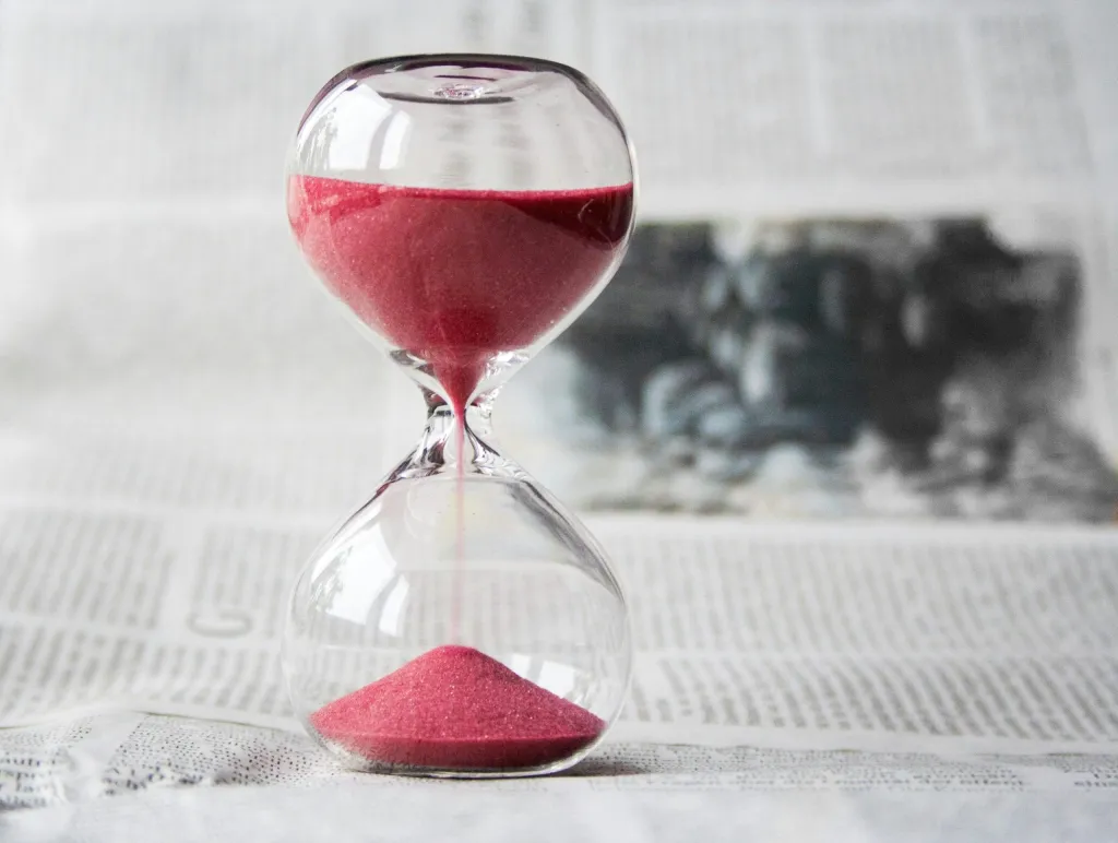 Hourglass with pink sand symbolizing time loss in small business operations, highlighting the need to save time running your business with custom software.
