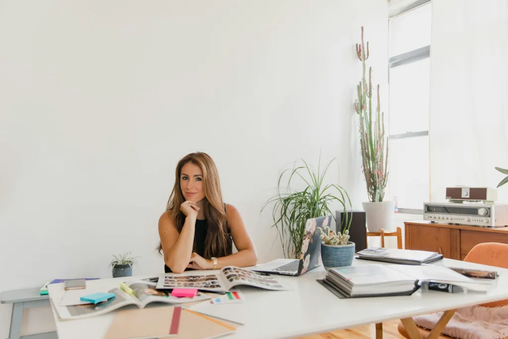 Small business owner at desk with books near bright window planning custom software