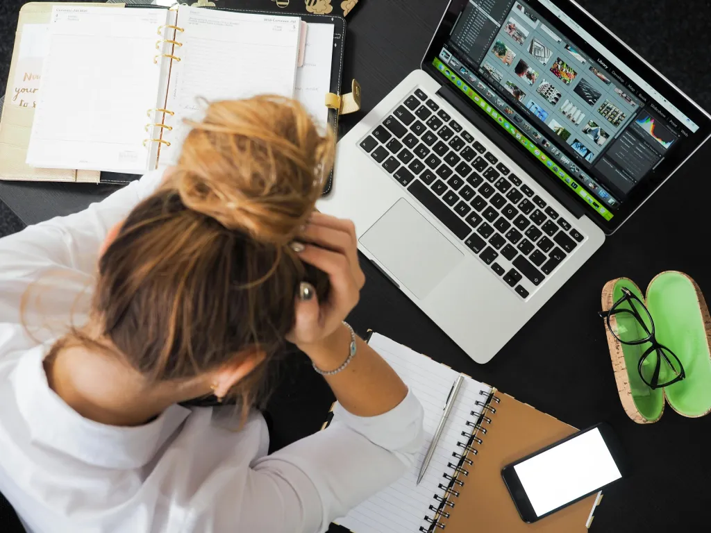 Female entrepreneur at her desk with a laptop, looking frustrated due to software development agency complaints.