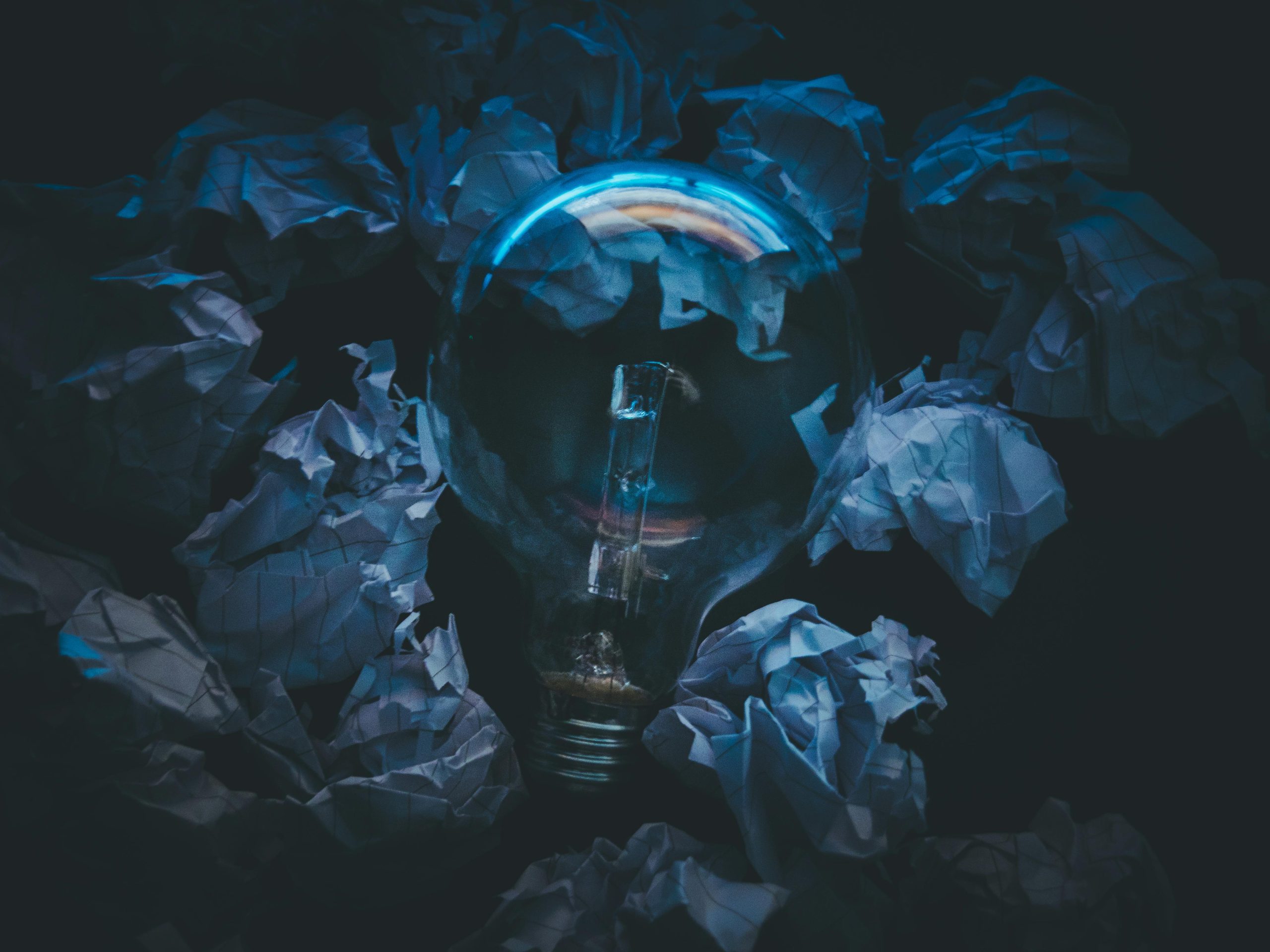 Glowing light bulb surrounded by crumpled paper representing breakthrough thinking in software development