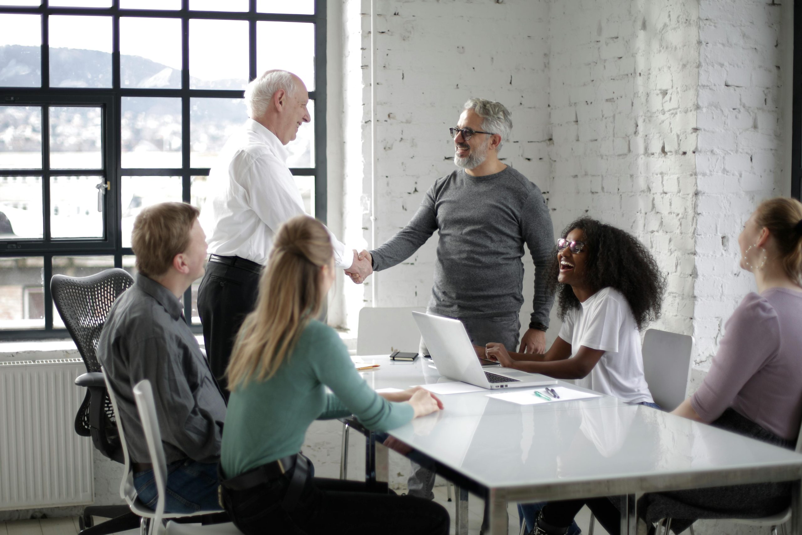 Business leaders and software developers shaking hands during a custom mobile app planning meeting